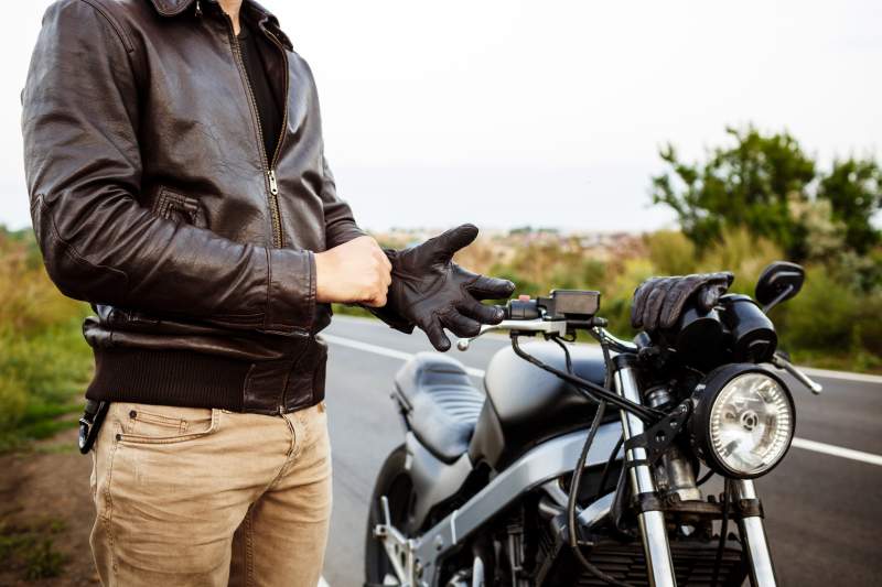 young-handsome-man-posing-near-his-motorbike-wearing-gloves