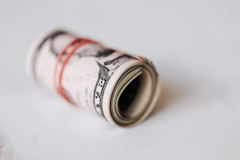 rolled-dollars-placed-on-white-surface